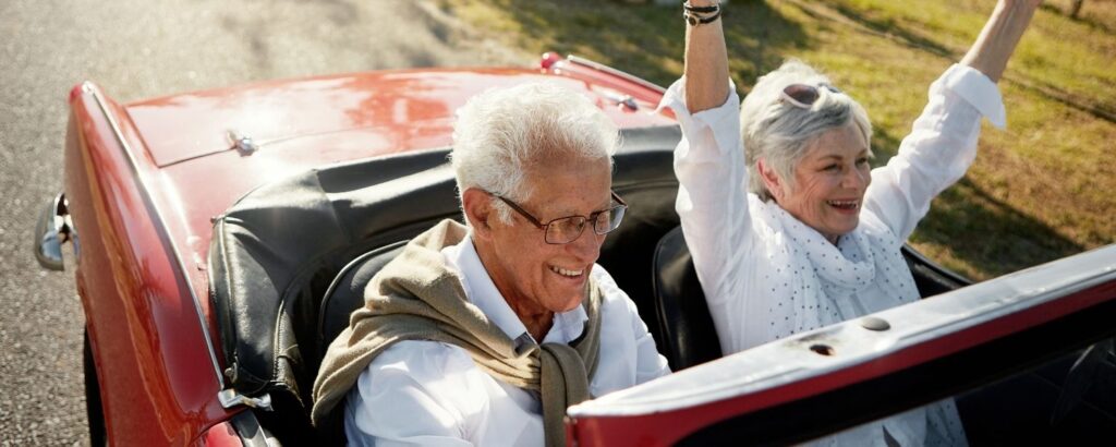 photo of a happy older couple in a red convertible