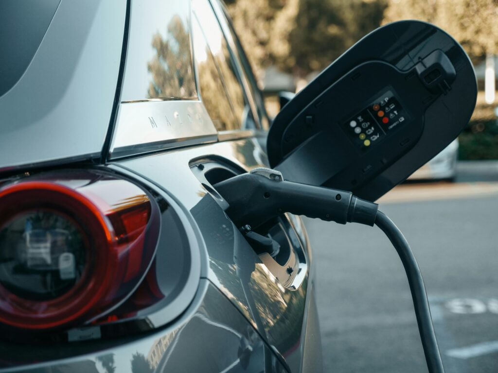 Electric car plugged into a charging station in a parking lot.