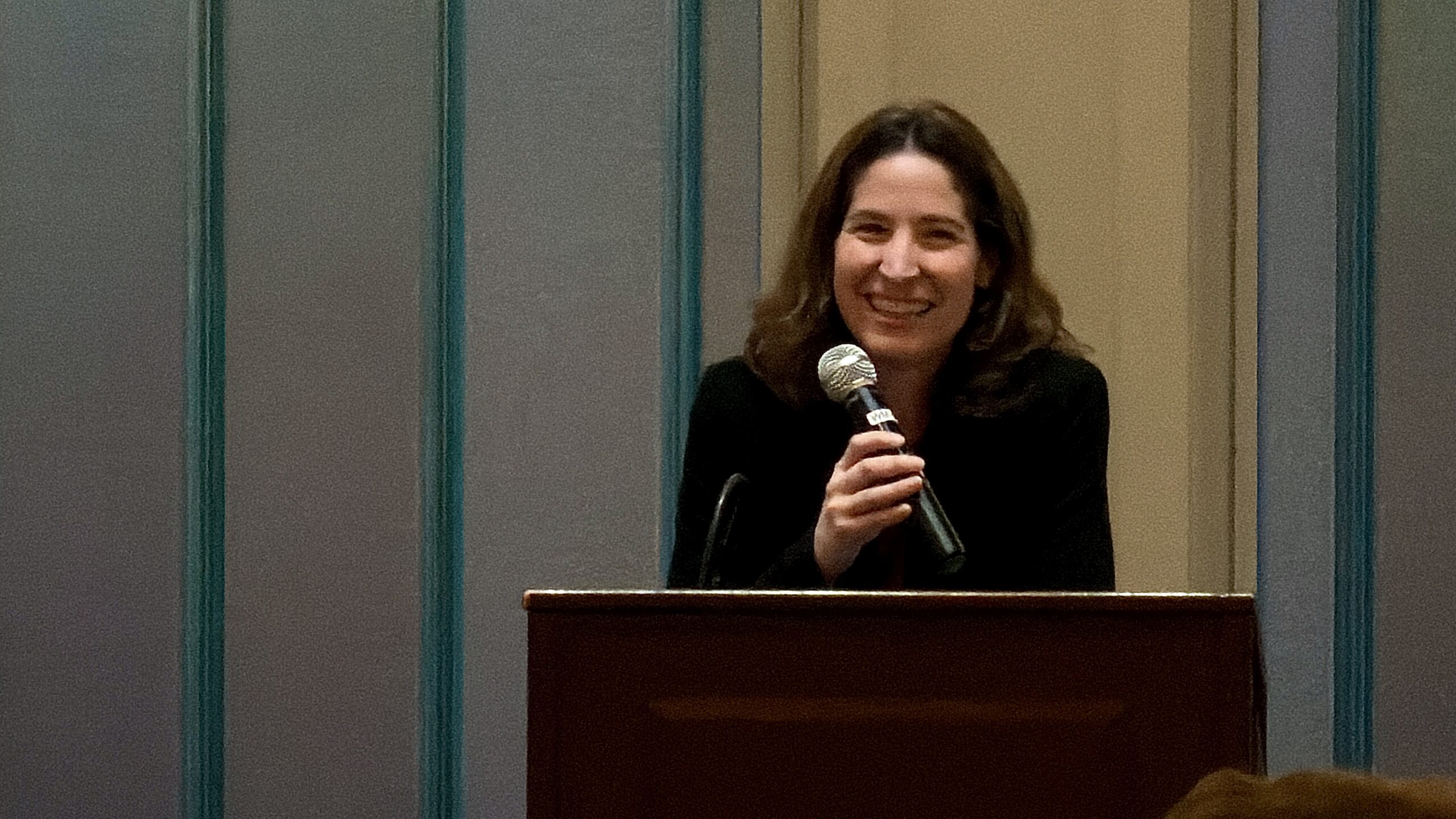 photo of woman at podium holding microphone